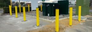 A row of bright yellow bollards is installed on a concrete surface