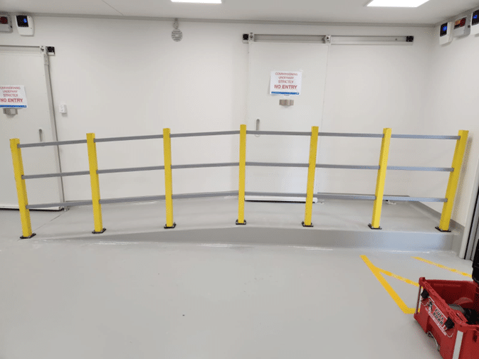 Safety railing installed along a small indoor access ramp.