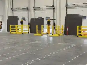 Yellow DEFLEX safety barriers installed in front of loading dock doors inside a warehouse